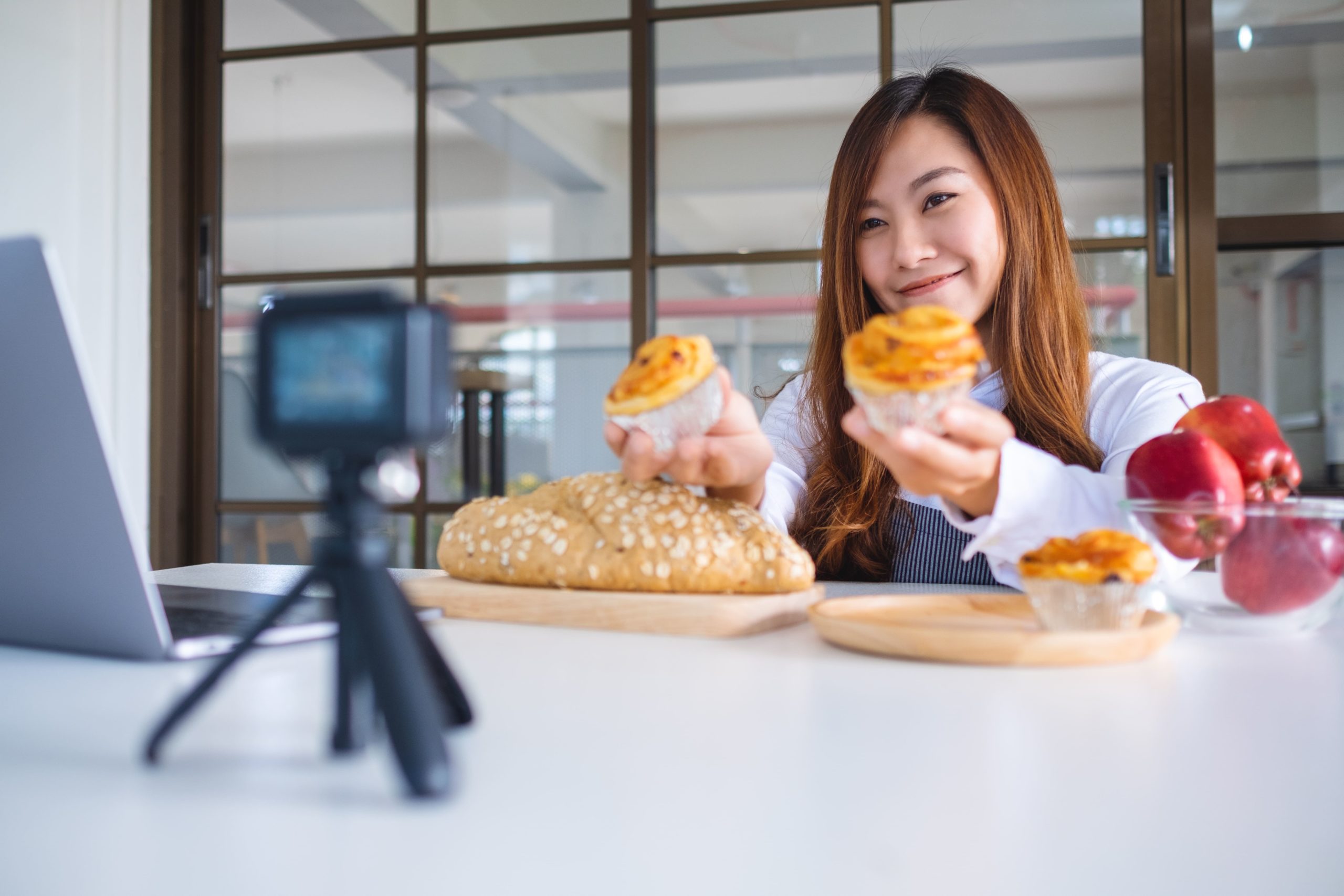 A female food blogger records a video showcasing muffins and bread as part of an influencer collaboration with a food and beverage PR agency