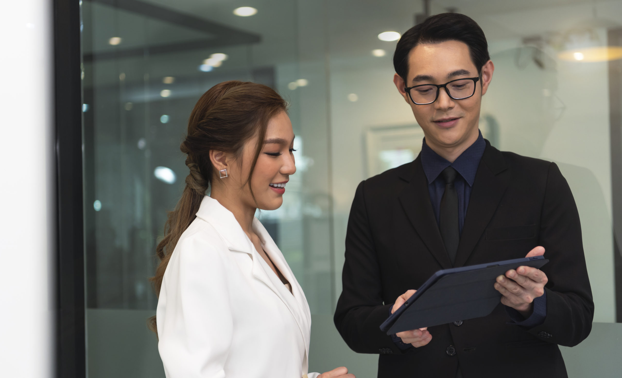 An expert from our press release agency in Singapore reviews a successful campaign strategy with a happy client on a tablet.